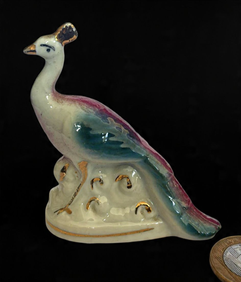 Escultura produzida em porcelana, representando pavão, maior comprimento 6,5 cm, década de 50, marcas do tempo.