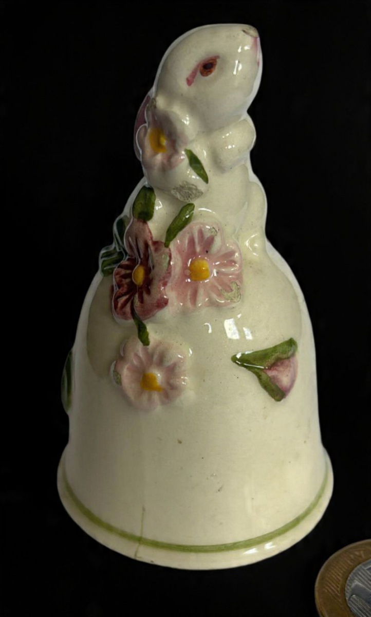 Sineta produzida em faiança, com decoração representando coelho e flores, maior comprimento 8,5 cm, meados do século XX, sem o pêndulo, com discretos bicados.