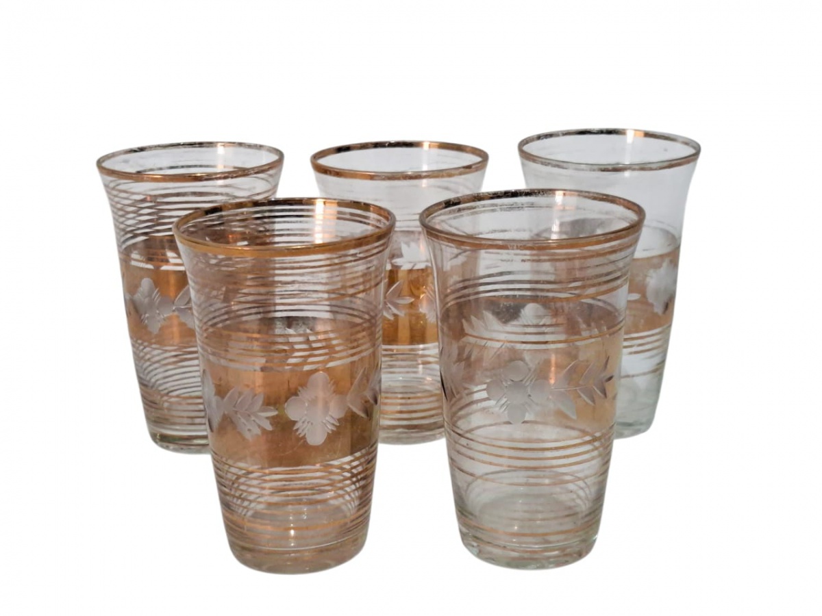 Conjunto de cinco copos de cristal com frisos dourados. com marcas de uso. 12cm.