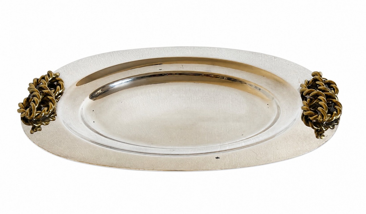 Bela bandeja espessurada a prata (Prata Wolff), ornada com dois pegadores dourados em forma de laços. 50cm. Um dos pegadores precisa de solda.