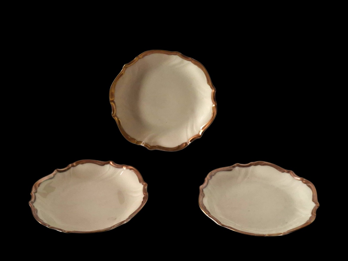 HUTSCHENREUTER – Belo e raro conjunto com três pratos de pão em porcelana alemã Hutschenreuter. Ressalta-se o valor das peças pela douração cuidadosa e pelo relevo etéreo que complementa a borda. 13cm.