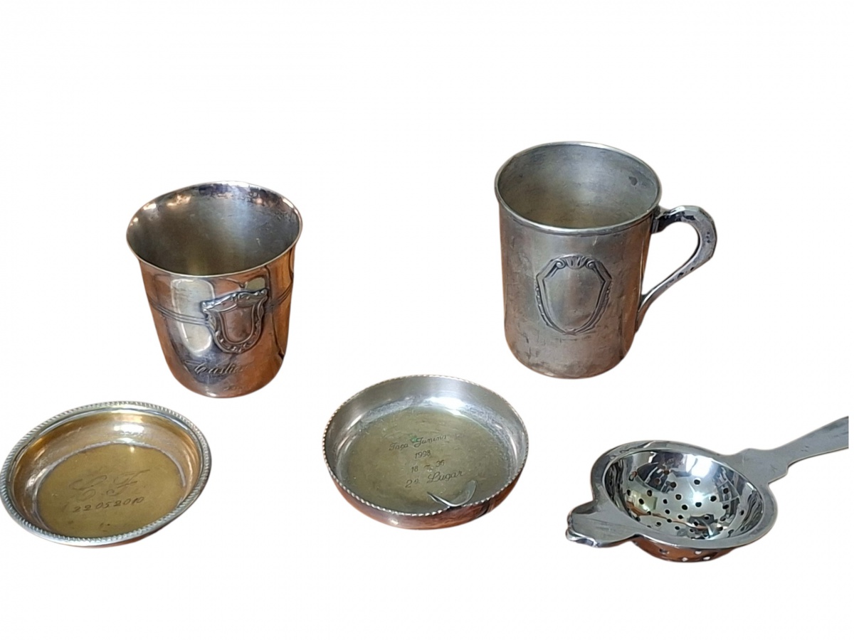 Conjunto com cinco objetos de metal, sendo quatro em metal espessurado a prata. Dois são copinhos pequenos e um é uma peneira para drinks.