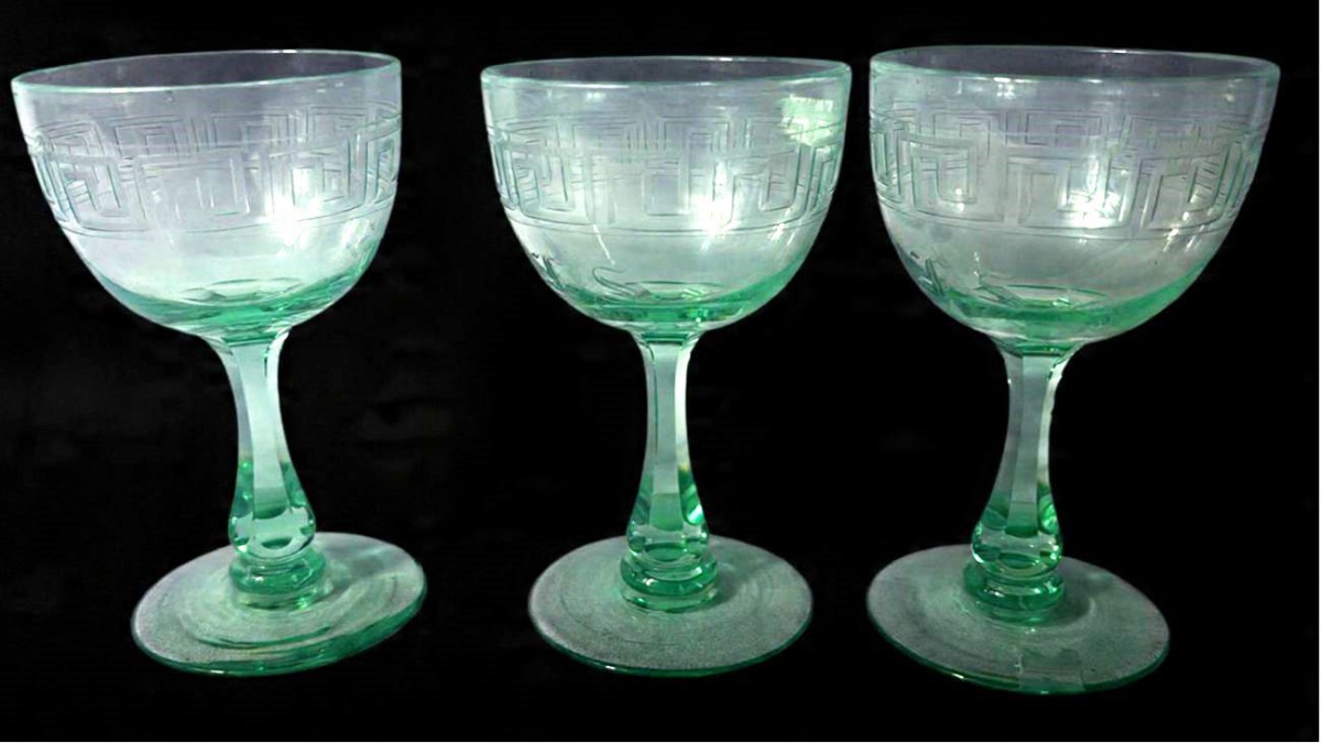 Lote contendo 3 taças produzidas em cristal verde, com desenhos em padrão Grego, com Monograma, no estilo Art. decó, com haste facetada e trabalhada, maior comprimento:12,5cm, uma com bicado na base.