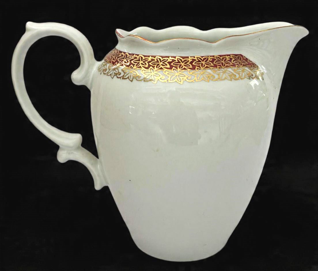 RENNER-Bela leiteira produzido em porcelana, com ornamentação de faixa vinho, com detalhes estilizado no formato de flor em filetação de ouro, maior comprimento:15cm altura/ 18,5cm comprimento.