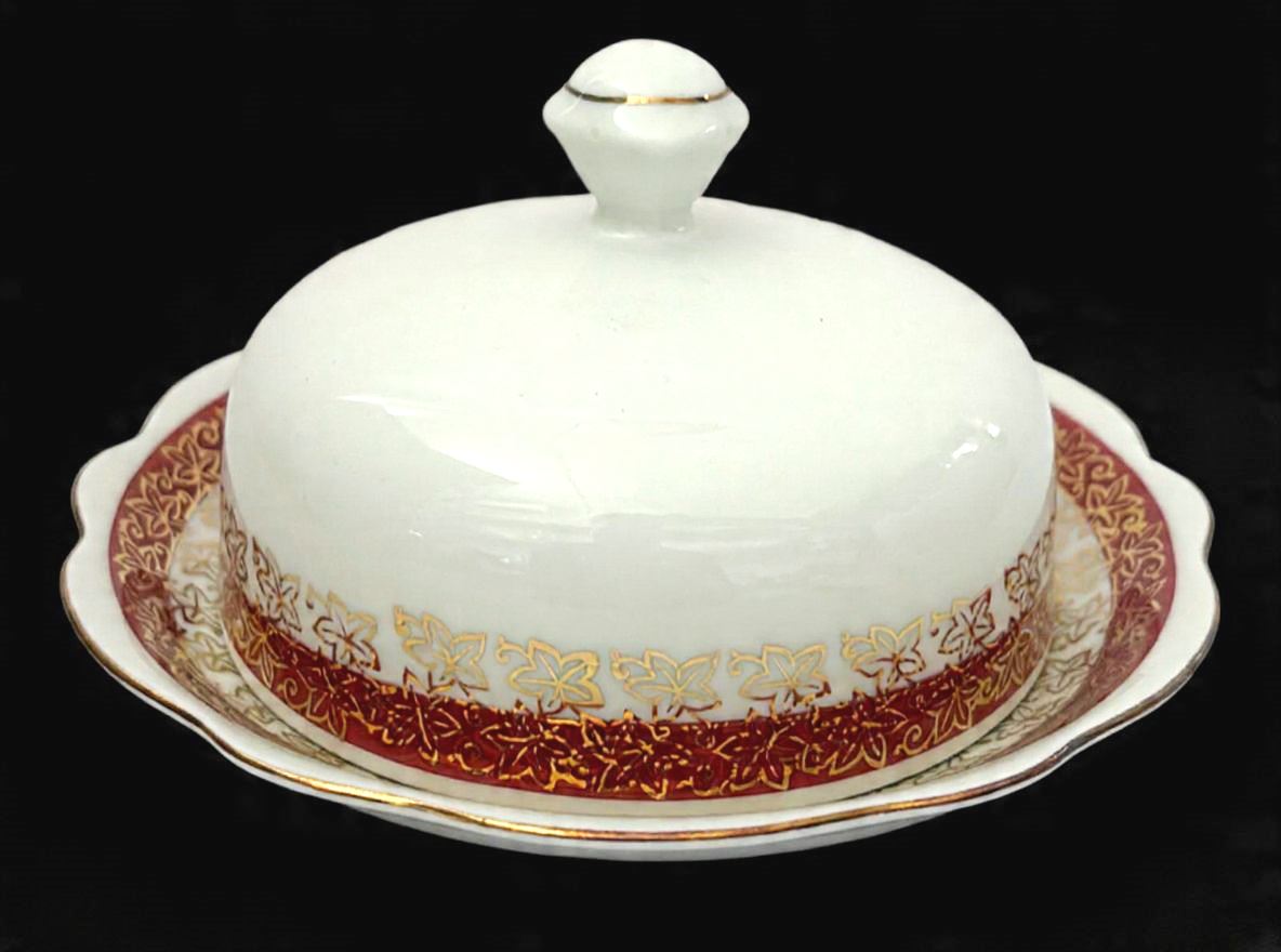 RENNER-Bela Manteigueira produzida  em porcelana, com ornamentação de faixa vinho, com detalhes estilizado no formato de flor em filetação de ouro, maior comprimento: 11,5cm diâmetro.