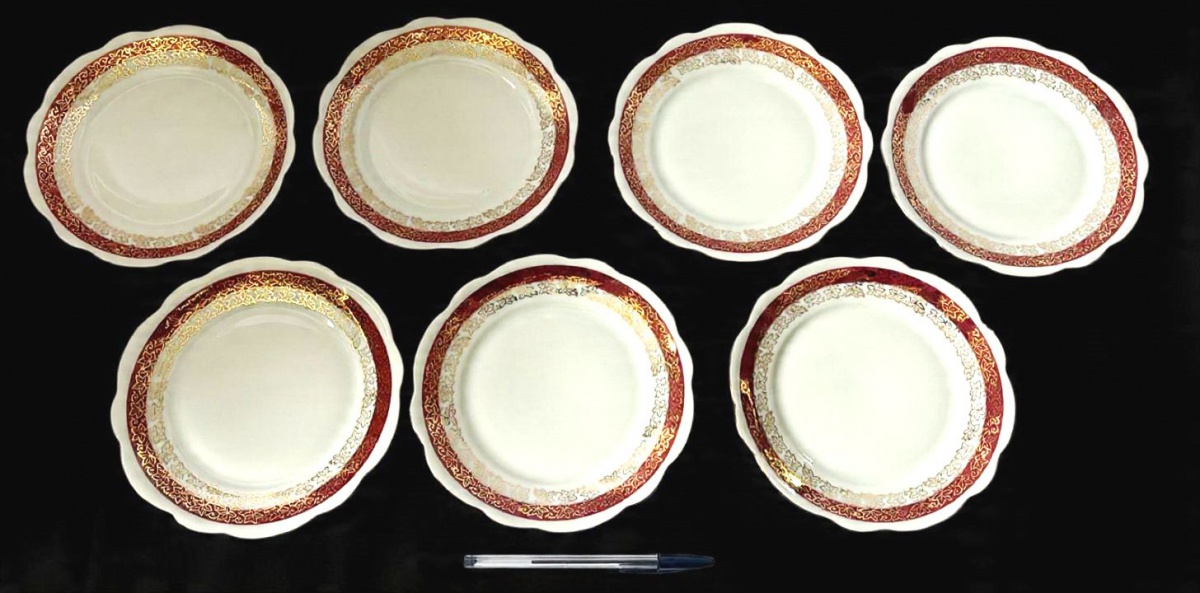 RENNER- Lote contendo 7 pratos para sobremesa, produzidas em porcelana, com ornamentação de faixa vinho, com detalhes estilizado no formato de flor em filetação de ouro, maior comprimento:18cm diâmetro.