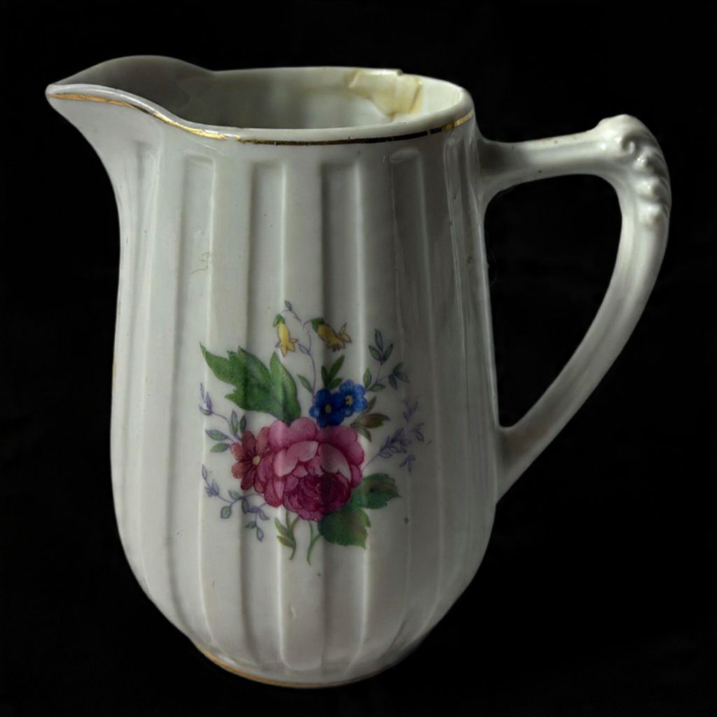 Cremeira produzido em porcelana, com corpo em gomos , decorado com ornamentações florais em rica policromia, possui restauro com fio de cabelo na borda, maior comprimento:9,5cm.