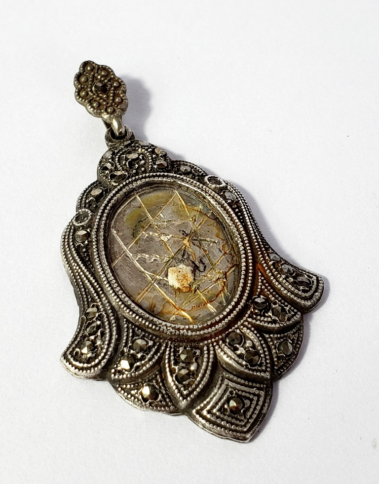 Pingente relicário, produzido em prata de lei, peso 11 gramas, com detalhes em pedras marcassitas, maior comprimento:5,5cm.