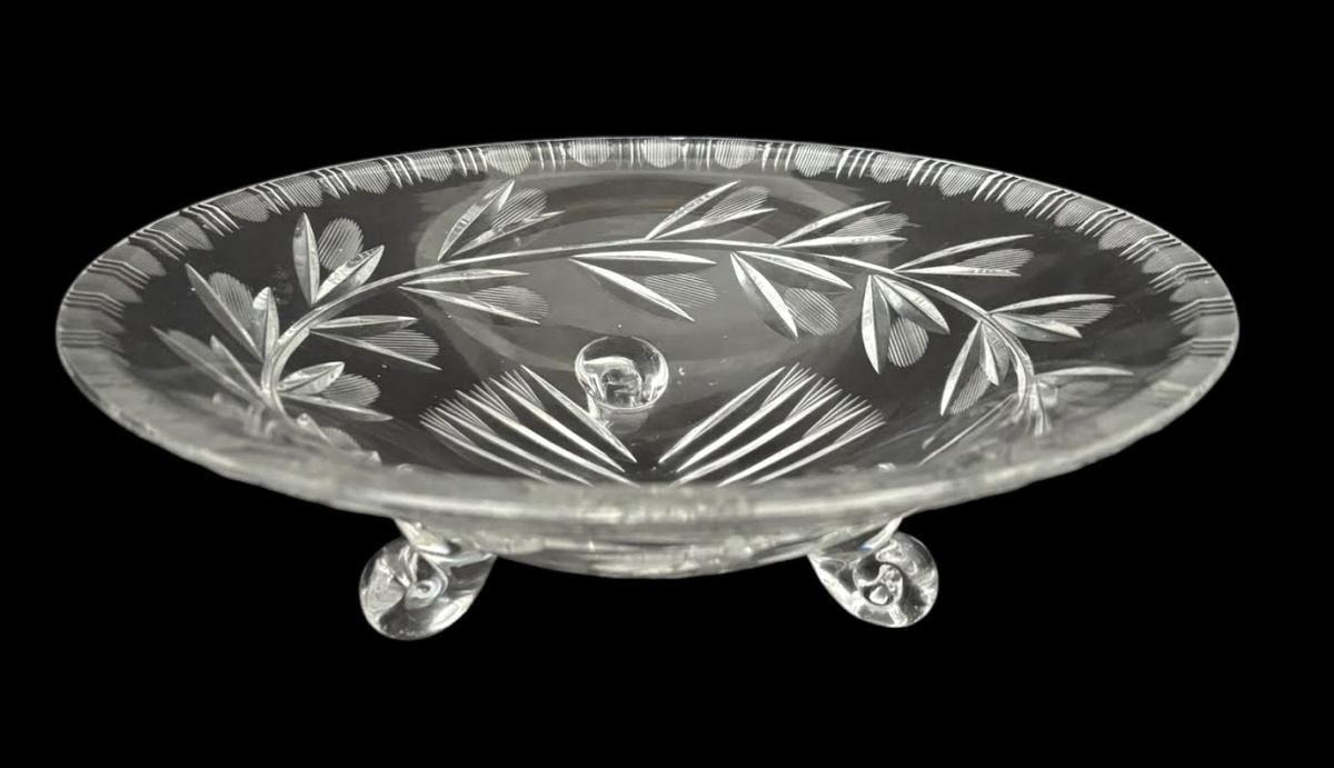 Centro de mesa em cristal lapidado, formato circular, com decoração vegetal em lapidação profunda e borda trabalhada. Apoiado sobre três pés integrados, peça elegante e decorativa, adequada para mesa ou aparador. Bom ...