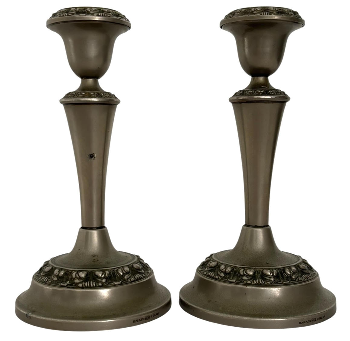 Par de castiçais em metal espessado a prata, fabricação inglesa, marca IANTHE, conforme inscrição Silver Plated  Made in England na base. Modelo de linhas elegantes com corpo afunilado e decoração em relevo floral nas ...
