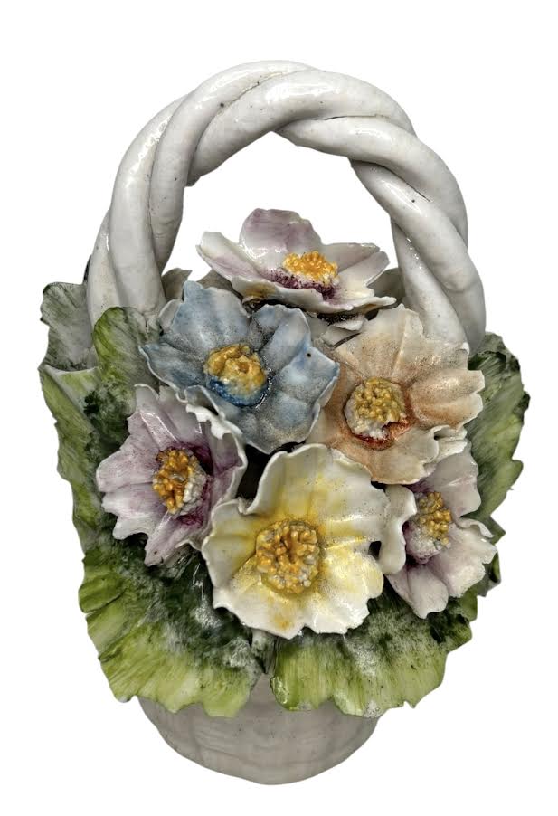 Cestinha decorativa em Capodimonte, ricamente modelada com flores policromadas em relevo e alça entrelaçada, sobre base texturizada simulando cestaria. Peça delicada, de caráter ornamental, com base revestida em feltro. ...
