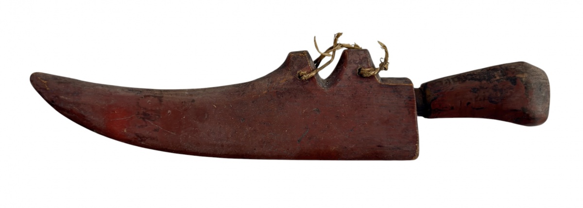 Faca antiga de trabalho, com lâmina em aço de formato curvo e cabo em madeira patinada pelo uso. Acompanha bainha artesanal em madeira entalhada, com amarrações em fibra natural. Peça de caráter rústico e etnográfico, ...