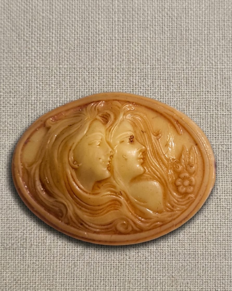 BROCHE EM MATERIAL SINTÉTICO, MEDINDO 5,5CM.