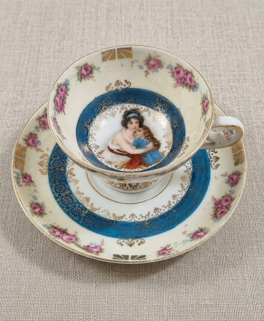 XÍCARA E PIRES EM PORCELANA EUROPÉIA, POSSIVELMENTE DO SÉCULO XIX, DA PRÚSSIA, DECORADA COM CENA MATERNAL. MEDIDA DO PIRES 13,5CM DE DIÂMETRO. MEDIDA DA XÍCARA 8,5CM DE DIÂMETRO X 6CM DE ALTURA.