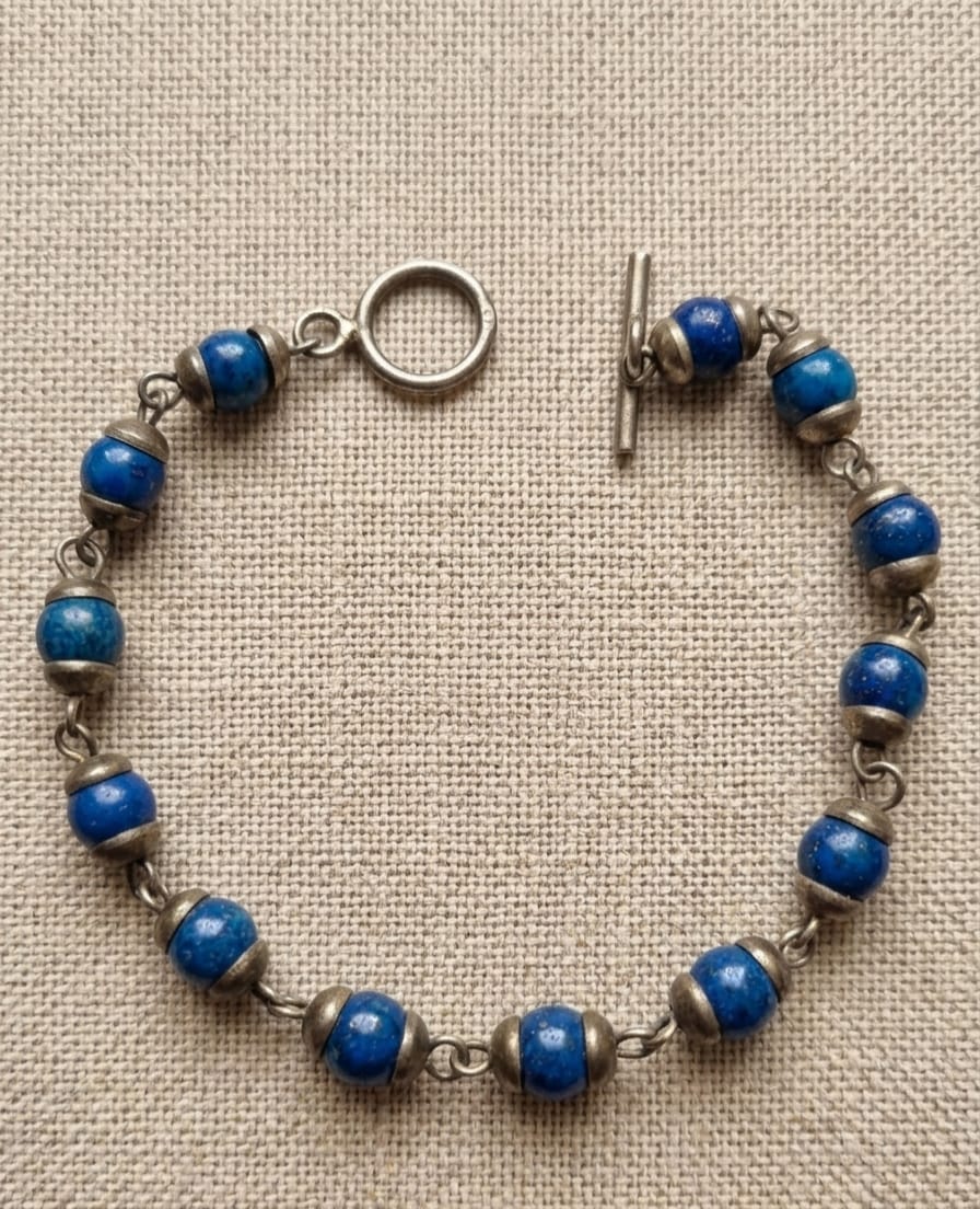 PULSEIRA EM PRATA DE LEI, COM ADORNOS DE COR AZUL, MEDINDO 19CM ABERTA.
