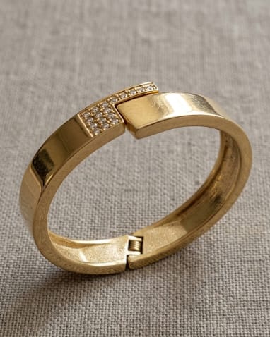 PULSEIRA DOURADA COM STRASS, MEDINDO 6CM DE DIÂMETRO.