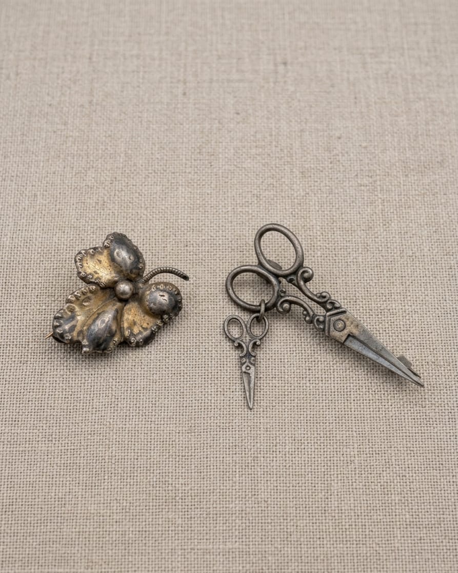2 BROCHES PRODUZIDOS EM PRATA DE LEI (FLOR) E METAL PRATEADO ( TESOURA). MAIOR 4CM.