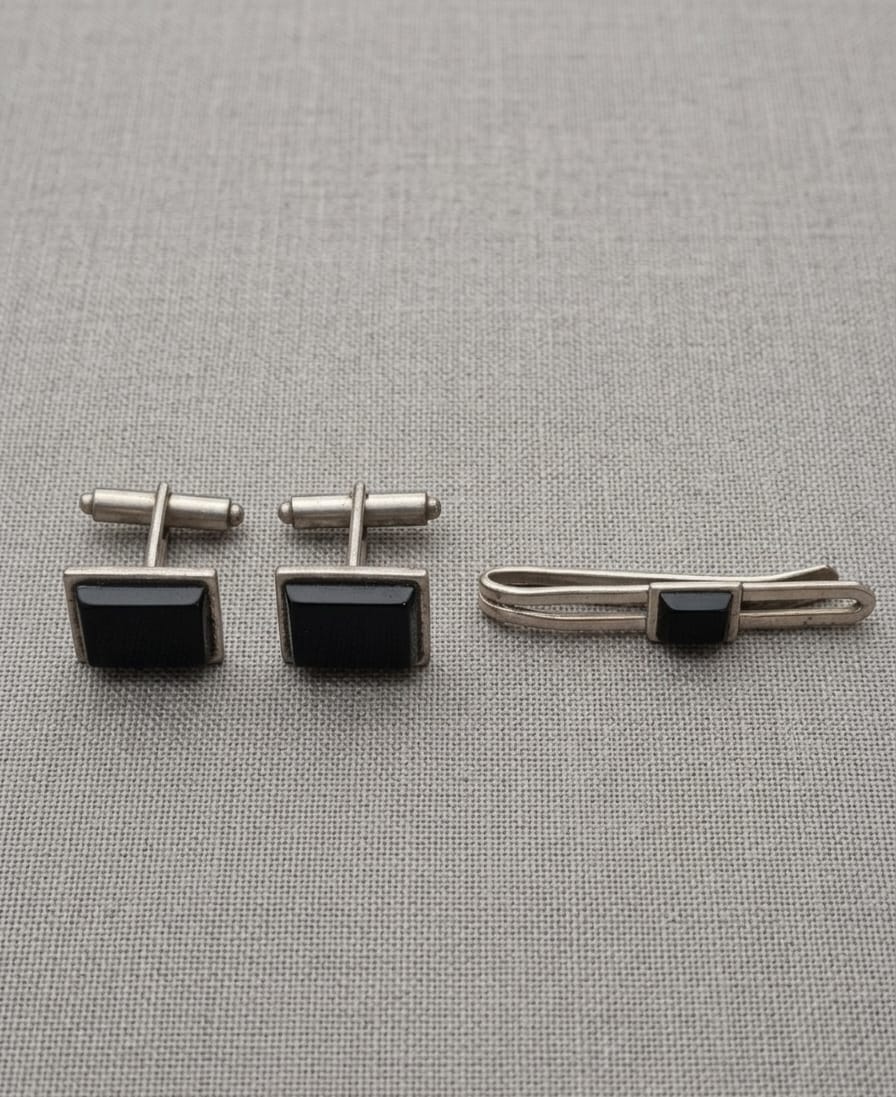 CONJUNTO DE ABOTOADURAS E PRENDEDOR DE GRAVATAS EM METAL PRATEADO E ADORNOS ESCUROS. MAIOR 4CM.