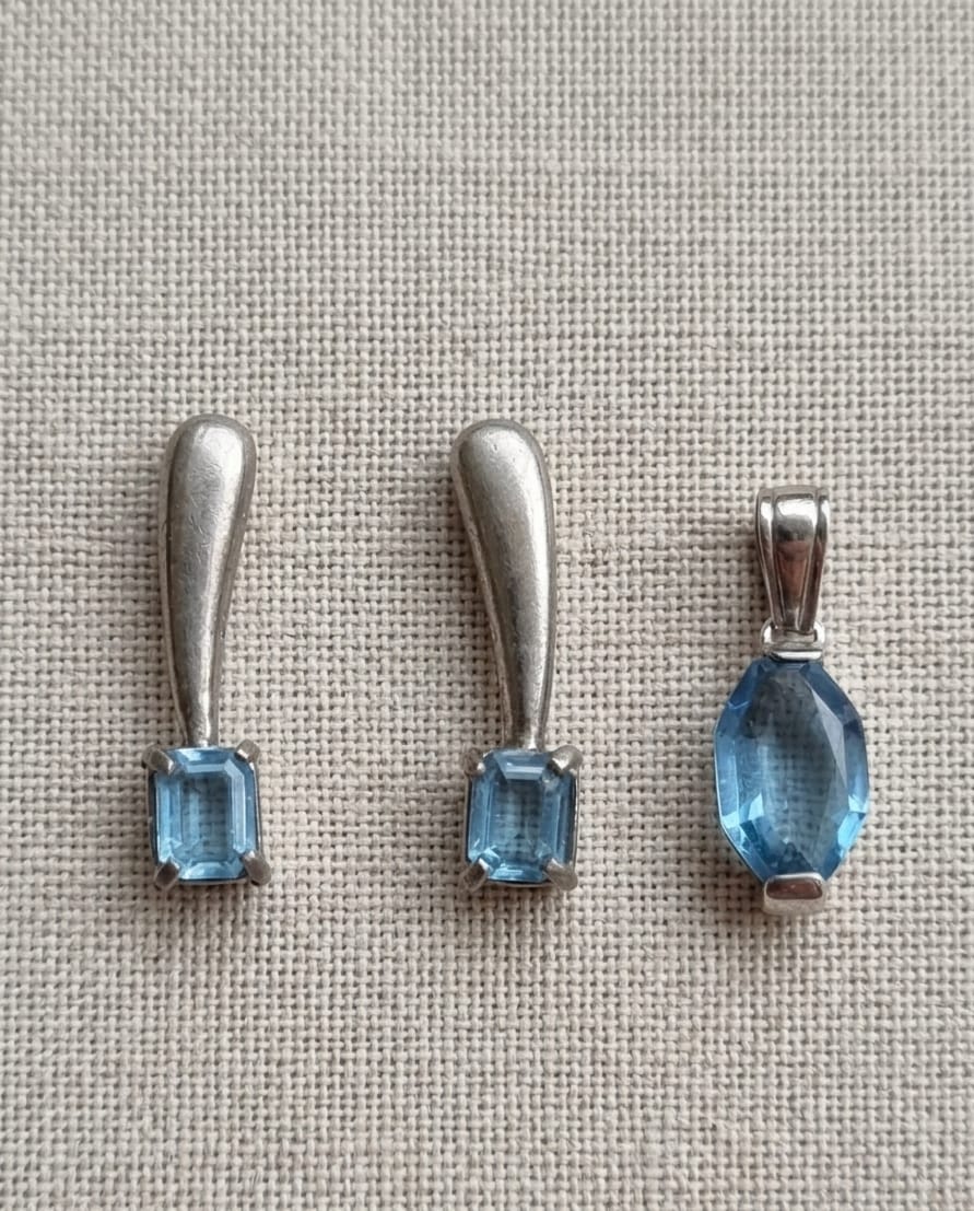 PAR DE BRINCOS E PINGENTE EM METAL  PRATEADO, DECORADOS COM PEDRAS SINTÉTICAS AZUIS. MAIOR 3CM.