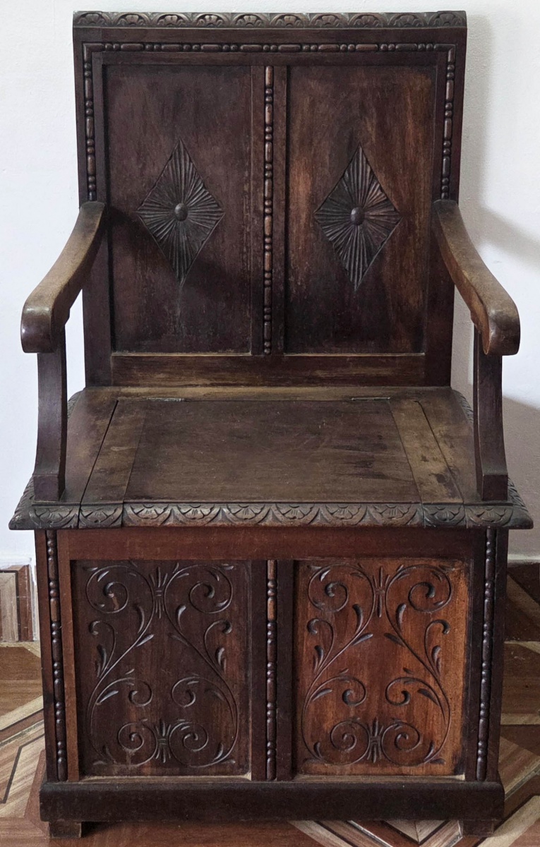 POLTRONA - de sacristia em madeira encosto com entalhe, parte frontal com almofadas e desenhos sulcados, guarda volume sendo o assento como tampa, moldura no assento trabalhado 100x60x48 cm