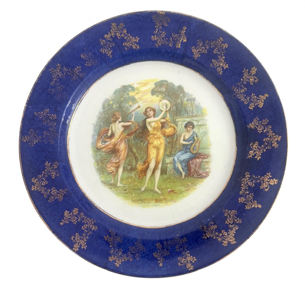 ENGLAND - Prato de coleção em porcelana cinglesa om ampla aba azul cobalto ricamente ornamentada com douração floral. Medalhão central policromado com cena alegórica clássica, representando figuras femininas em ambiente ...