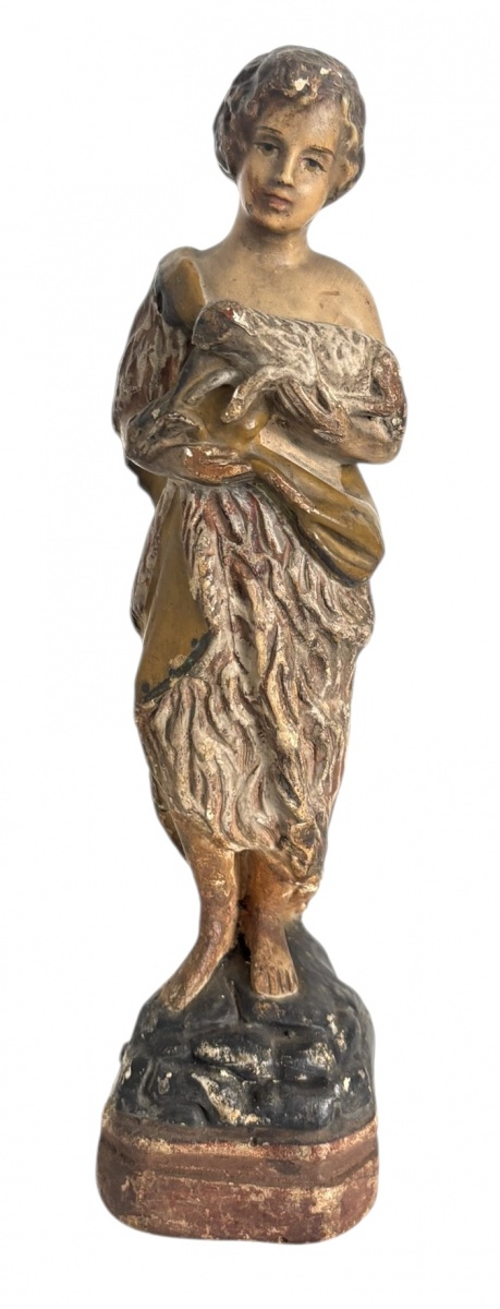 Imagem sacra representando São João Batista em estuque policromado em postura clássica, segurando elemento junto ao corpo, sobre base integrada. Peça de caráter sacro, com pátina natural do tempo e sinais compatíveis ...