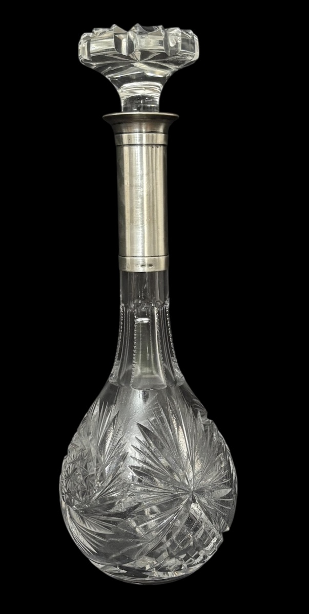 Garrafa Baccarat em cristal francês, corpo bojudo ricamente lapidado com motivos em estrela e gomos, gargalo de prata de lei facetado e tampa original. Peça de elegante presença, brilho intenso e acabamento refinado, ...