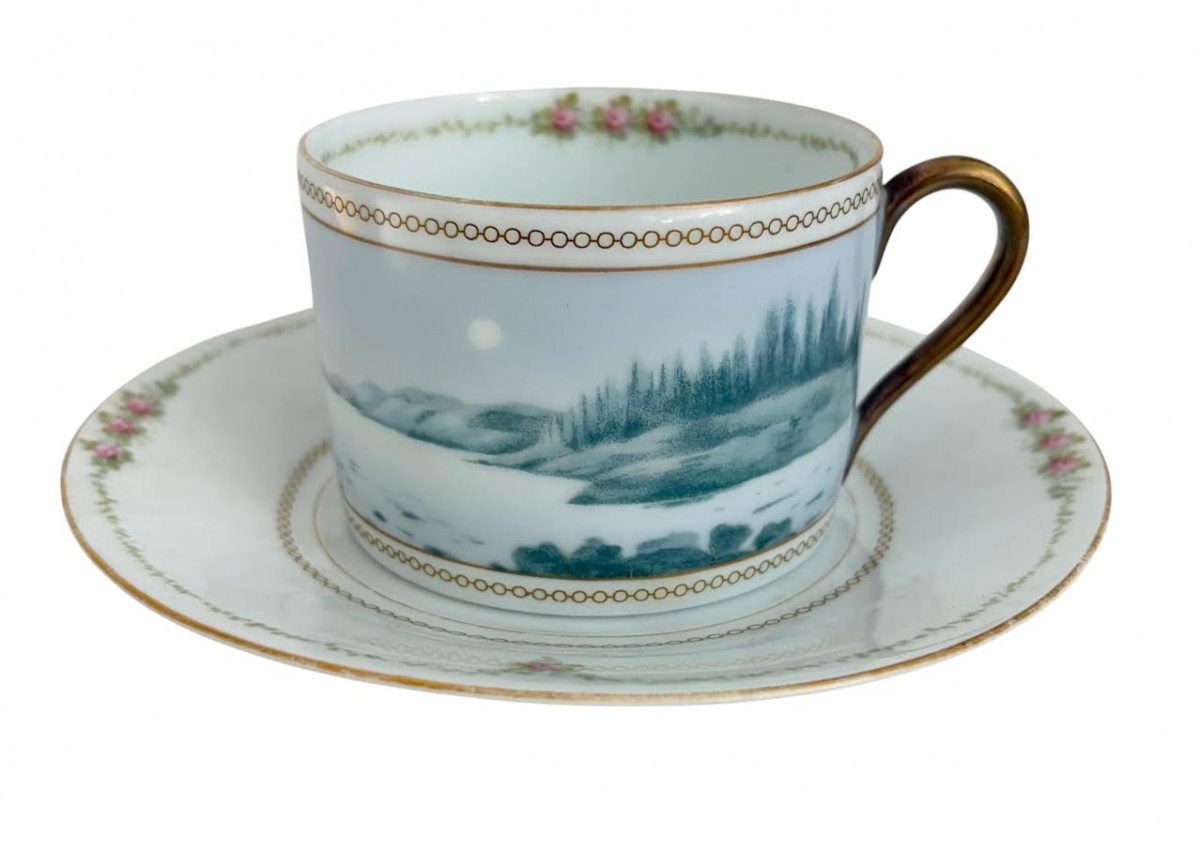 Xícara de chá com pires, em porcelana Rosenthal, decorada com paisagem em tom verde, frisos dourados e guirlandas florais.