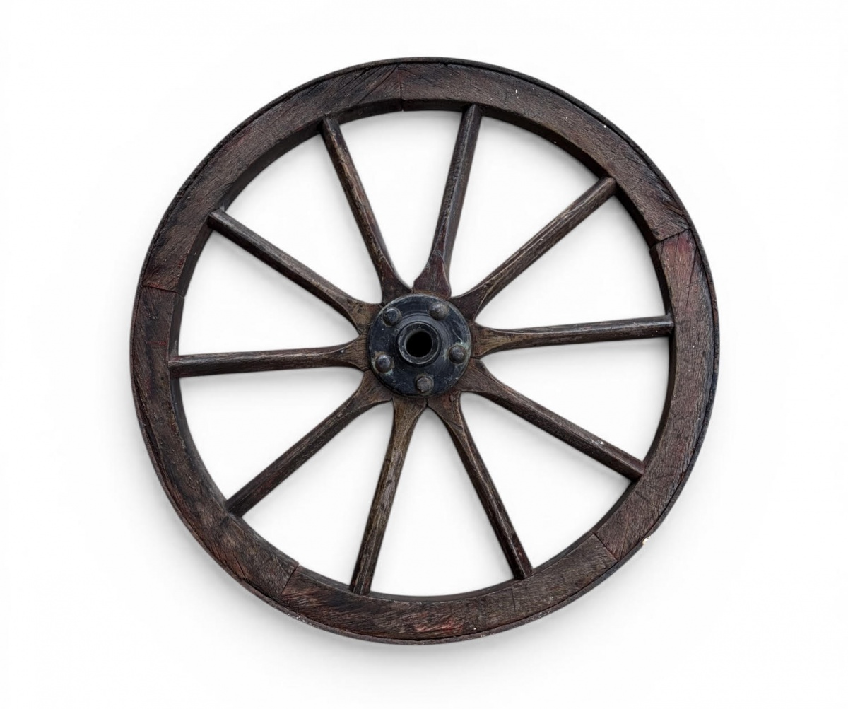 Roda antiga de carroça em madeira, com aro segmentado e cubo central em ferro fundido composta por raios torneados. Peça rústica com forte apelo decorativo, apresentando pátina e sinais de uso compatíveis com a idade. ...
