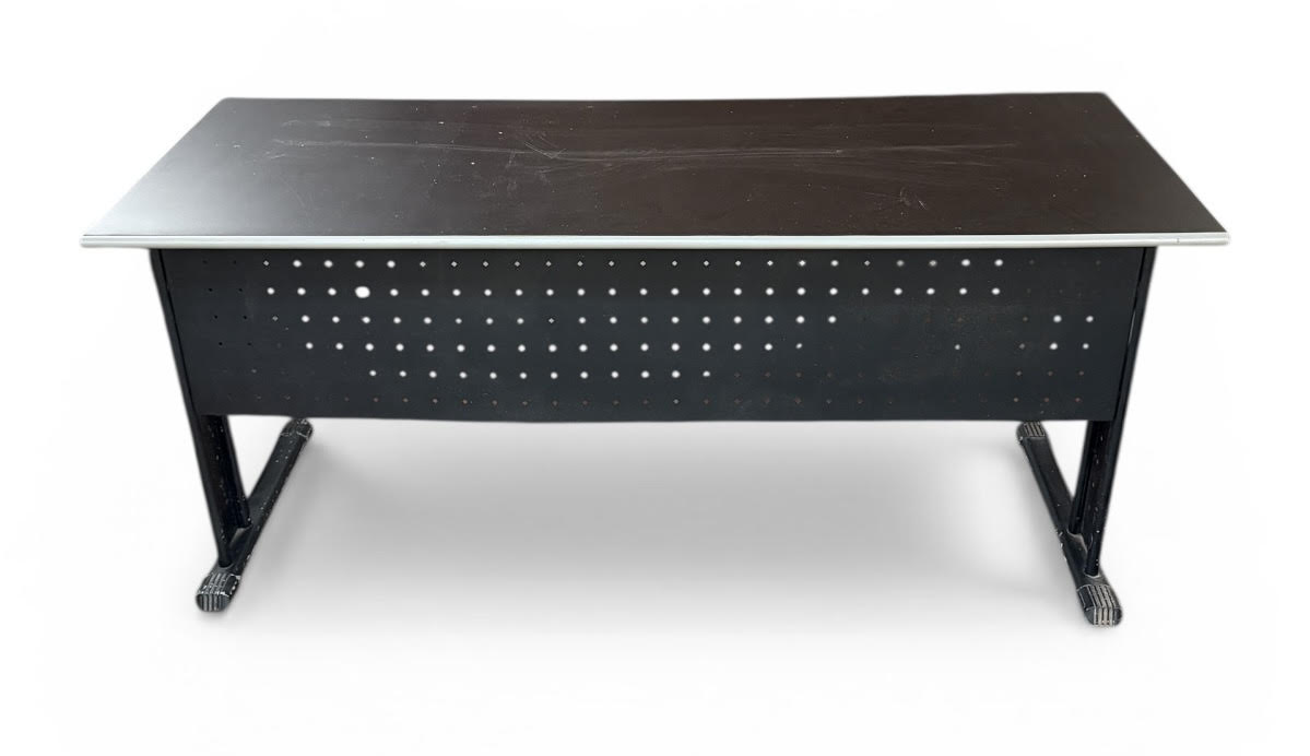 Mesa de escritório em metal com tampo retangular, estrutura tubular e painel frontal perfurado, estilo industrial. Acabamento em pintura preta, apresentando sinais de uso e desgaste no tampo. Mede 75 cm altura x 1,60 cm ...
