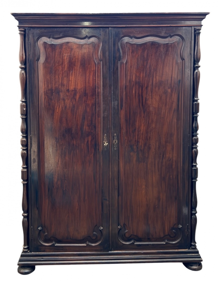 Armário antigo de duas portas, em madeira nobre canela, com painéis almofadados e colunas torneadas laterais. Interior com cabideiro superior e amplo espaço para armazenamento. Peça de linhas clássicas, robusta e ...