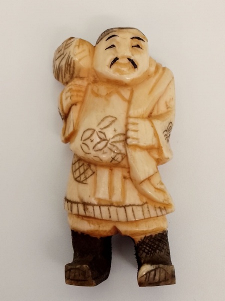 MARFIM / JAPÃO  ( Era Meiji - 1868/1912) - Netsuke, de coleção, confeccionado em marfim japonês policromado finamente lavrado na representação de homem carregando ferramenta. Dimensão: 5 cm de altura.