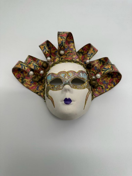COLECIONISMO -  Lote contendo 01 (uma) máscara veneziana para adorno de parede, confeccionada em faiança, pintada à mão, ornamentada com desenhos artesanais ricamente policromados. Medida: 18 cm.