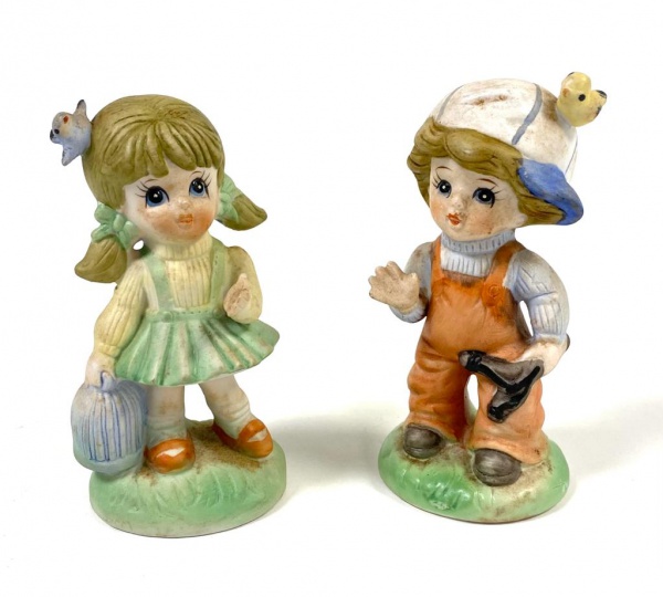 Par de graciosas estatuetas em biscuit representando casal de crianças.  Altura 12cm