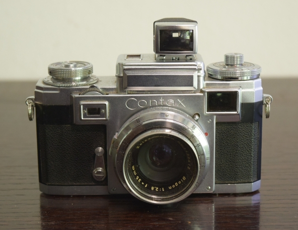 Máquina fotográfica analógica `CONTAX`, lente Zeiss Optom Biogon  1: 2,8  f = 35mm, com visor acoplado, sem estojo.  Material estava guardado, estamos vendendo no estado em que se encontra.