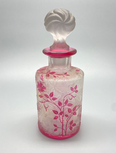 DEMI CRISTAL - Perfumeiro VAL SAINT LAMBERT (Cristal Belga, desde 1826), em formato cilíndrico, fosco, decorado com flores e folhagens, clarificadas com ácido, facetas recortadas no gargalo, tampa acidada com folhagens em tom rubi. Alt. 16 cm. Não assinada.