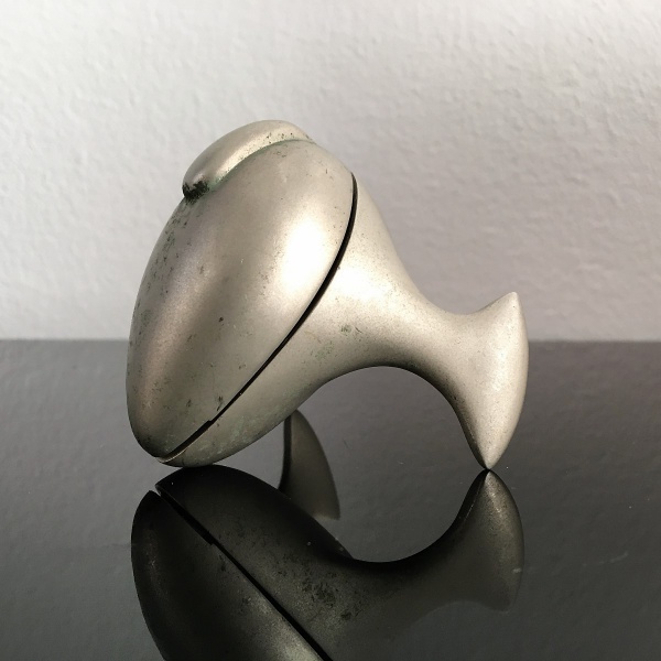 Artefato em metal cinzelado com formato anatômico. Dimensões: 5,5 cm x 6,6 cm x 6 cm.