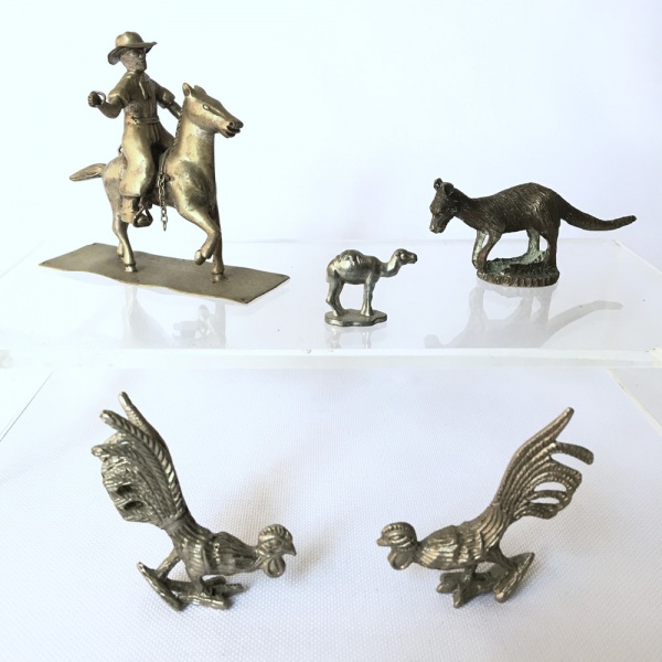 Parte de coleção com 5 miniaturas em metal cinzelado. Par de galos, camelo, canguru e cavaleiro gaúcho. Dimensões: Maior peça 8 cm altura / menor peça 2 cm altura.