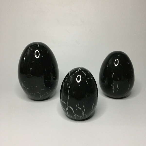 Conjunto com 3 ovos em pasta de vidro, decorados com linhas brancas sobre fundo preto. Dimensões: 12,5 cm (maior peça).