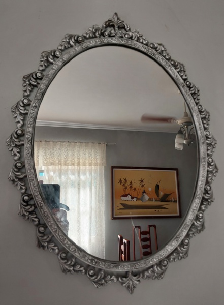Antigo e belíssimo espelho oval, moldura em metal prateado decorada em arabescos. Medida: 60 cm de altura x 46 cm comp. OBS: pequeno arranhão no espelho.