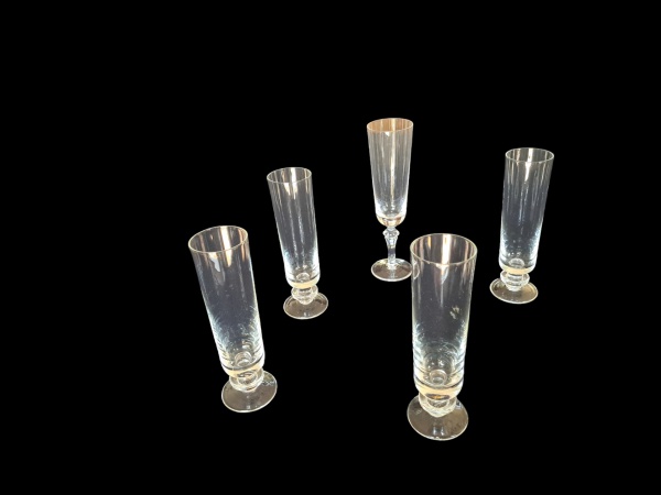 Cinco flutes em cristal translúcido, uma delas Strauss marcada na base, Alt. 20 e 18, Diam. 5 cm.