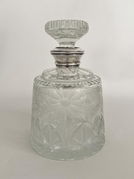 Pesada e vistosa garrafa em cristal lapidado com motivo floral, gargalo em prata teor 975. Med: 21,5 x 14,5 diâmetro.