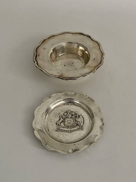 Dois pratos em prata. O menor com Brasão em relevo no centro. Teor 900.  Med: 12 cm. e 10 cm. diam. Peso: 145 g.
