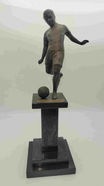 Antigo troféu de futebol em metal representando um jogador chutando uma bola com base em pedra. Cons