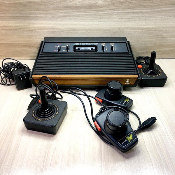 Console Atari 2600 funcionando com 2 controles, fonte compatível e par de controles paddle. no estad