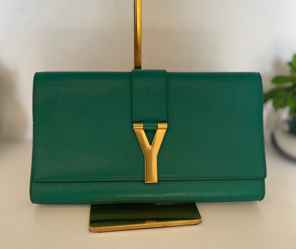 YVES SAINT LAURENT - Clutch Saint Laurent Classic Y Preta Original, confeccionada em couro calf liso  verde . Possui modelo retangular compartimento único, um bolso interno, forro em camurça, detalhe frontal com a letra Y em ferragem dourada e fecho por aba e botão magnético. Acompanha certificado e cartão de cuidados da marca. medidas: 28x 16 cm de altura  Seminova, em ótimo estado de conservação
