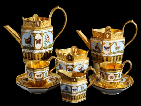 Tête-à-tête para chá e café em porcelana KPM, ricamente policromado e dourado, decorado com borboletas; composto de 2 bules ( o maior: 19x21x9cm.), leiteira, açucareiro e 2 xíc. de chá c/ pires. Muito bem conservados.