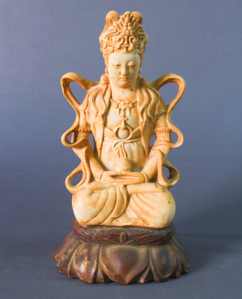 Escultura oriental em resina representando figura em posição de meditação sobre base em formato de f