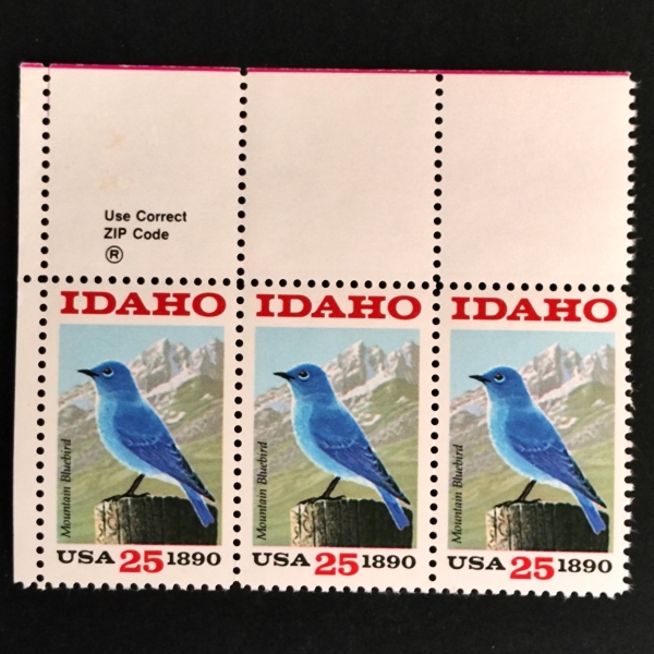 Três selos postais dos Estados Unidos, cada um com a inscrição IDAHO e Mountain Bluebird, aprese