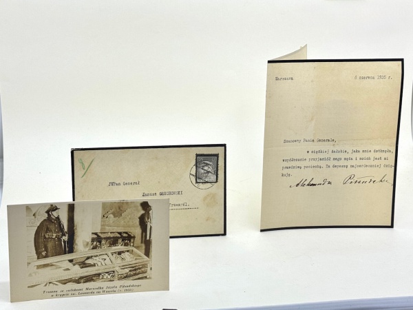 CARTA DATILOGRAFADA E ASSINADA POR ALEKSANDRA PILSUDSKA (VIÚVA DO MARECHAL JÓZEF PILSUDSKI) / DESTINATÁRIO: GENERAL JANUSZ GLUCHOWSKI / POLÔNIA, 06 DE JUNHO DE 1935 (15,5x19cm). Com envelope original circulado, datado de 06 de junho de 1935, remetido de Varsóvia para o General Janusz Gluchowski em Przemysl, contendo no interior cartão dactilografado de pêsames assinado por Aleksandra Pilsudska, viúva do Marechal Józef Pilsudski (1867-1935), Chefe de Estado e posteriormente "Naczelnik" da Segunda República Polonesa, figura central da independência da Polônia no pós-Primeira Guerra Mundial e artífice da política nacional até sua morte em 12 de maio de 1935. O documento foi enviado menos de um mês após o falecimento do Marechal, no contexto do luto oficial que se estendeu por todo o país, contendo mensagem de agradecimento dirigida ao General Gluchowski pela solidariedade recebida. O texto, redigido em polonês, refere-se "à dura aflição que me atingiu", agradecendo pelas condolências transmitidas e destacando que a manifestação do amigo de seu marido e dela própria constitui "verdadeira consolação". A assinatura manuscrita de Aleksandra Pisudska, viúva e destacada figura pública ligada ao movimento socialista pró-independência desde o início do século XX, reforça a relevância histórica do documento, que testemunha a rede de relações militares e políticas da elite dirigente polonesa no período imediatamente anterior ao colapso do Estado em 1939. Peça diretamente associada à memória oficial do Pilsudskismo e ao grupo militar que sustentava o regime à época. Envelope com selo polonês de 25 Groszy e carimbo postal legível. Ótimo estado geral de conservação. Acompanha o lote, ainda, um cartão-postal a seguir descrito: CARTÃO-POSTAL / CAIXÃO COM OS RESTOS MORTAIS DO MARECHAL JÓZEF PILSUDSKI NA CRIPTA DE SÃO LEONARDO / WAWEL (1935)  Cartão-postal fotográfico polonês (14x9cm) apresentando a urna mortuária com os restos mortais do Marechal Józef Pilsudski (18671935), exposta na cripta de São Leonardo, no Castelo de Wawel, em Cracóvia, no ano de 1935, durante o período de velório público e guarda de honra militar. A imagem mostra o esquife ornamentado em estrutura de vidro, ladeado por soldado polonês em uniforme cerimonial, no interior da cripta histórica destinada a heróis nacionais da Polônia. Verso no formato "POST CARD / CORRESPONDENCE", típico da impressão entre as décadas de 1930 e 1940, sem indicação do editor. Exemplar com carimbo no verso identificando antiga procedência: "ZE ZBIORÓW KRZYSZTOFA GLUCHOWSKIEGO" (Dos acervos de Krzysztof Gluchowski). Conservação em muito bom estado. *ALEKSANDRA PILSUDSKA (1882-1963), remetente e subscritora da carta em comento, nasceu em Suwalki, foi uma ativista política e primeira-dama da Polônia. Estudou no ginásio de sua cidade, então no Império Russo, e depois na Flying University. Em 1904, ela se juntou ao Partido Socialista Polonês, enquanto trabalhava em uma fábrica em Varsóvia. Ela também se junta à Organizacja Bojowa, o braço militar do partido. Em 1907 foi presa em Danillowicze e depois transferida para a prisão de Pawiak. Passou por Kiev, Lwow e se juntou à organização paramilitar Zwiazek Strzelecki (União das Sociedades de Tiro). Durante a Primeira Guerra Mundial, ela foi agente de ligação para o Primeiro Regimento da Legião Polonesa e depois para a Organização Militar Polonesa. Novamente presa, foi libertada pelo Ato de 05 de novembro. Ela foi membro da Rodzina Wojskowa ("Família Militar"), uma associação que ajudou órfãos da Grande Guerra. **O GENERAL JANUSZ JULIAN GLUCHOWSKI, destinatário da carta, foi um General de Divisão do Exército Polonês na Segunda República Polonesa. Nasceu no dia 06 de agosto de 1888, em Bukowa. Lutou nas Legiões Polonesas na Primeira Guerra Mundial, na Guerra Polaco-Ucraniana, na Guerra Polaco-Soviética e na Invasão da Polônia pela Alemanha Nazista, República Eslovaca e União Soviética em 1939, o que culminou no início da Segunda Guerra Mundial. Na adolescência frequentou o ensino médio em Czstochowa. Em 1905 tornou-se membro da Organização de Combate do Partido Socialista Polonês e foi ferido em uma mão durante um ataque perto de Czstochowa. Para evitar a prisão pelas autoridades russas, partiu para a Bélgica, onde estudou na Universidade de Liege. Retornou à Polônia dividida por volta de 1910 e se estabeleceu na Galícia austríaca. Em 1912 graduou-se na Escola de Oficiais da Associação de Fuzileiros em Stroza, perto de Cracóvia. Nos idos de agosto de 1914, comandou um pelotão em Oleandria e foi representante de Wadysaw Belina-Pramowski durante o lendário ataque dos chamados Sete Lanceiros de Belina (Uaska siodemka). Em 06 de agosto, juntamente com a Primeira Companhia de Quadros, deixou Cracóvia e marchou para Miechow. Em outubro de 1914 foi promovido a Tenente (Poruchik) e, em novembro de 1916, a Rittmeister (Mestre de Cavalaria). Até 1917 serviu no Primeiro Regimento Uhlan das Legiões Polonesas. Após a Crise do Juramento (Kryzys przysigowy) foi internado primeiro no Forte Beniaminow e, posteriormente, em Werl. Libertado em outubro de 1918, foi para Lublin, onde, no início de novembro, formou o Terceiro Regimento de Ulan (mais tarde renomeado para Sétimo Regimento de Ulan de Lublin). Junto com sua unidade lutou na Guerra Polaco-Soviética. No dia 29 de maio de 1920 foi promovido a Polkovnik. Foi transferido em julho de 1920 para a Galícia Oriental, assumindo o comando da Primeira Brigada de Cavalaria, lutando contra os soviéticos na Galícia e na Volínia. Após a guerra permaneceu no cargo até 1925, quando foi transferido para a Quarta Brigada de Cavalaria. Promovido a General de Brigada em 16 de março de 1927. Nomeado comandante do Centro de Estudos Militares Superiores a 04 de junho de 1930 e, três anos depois, após a morte do General Stanislaw Tessaro, foi nomeado comandante do Distrito Militar X em Przemyl. Em outubro de 1935 tornou-se vice-ministro dos Assuntos Militares. Nos primeiros dias da Invasão da Polônia em 1939, Gluchowski ordenou ao General Walerian Czuma que preparasse a defesa de Varsóvia. Em meados de setembro de 1939, fugiu para a Romênia. Após a fuga, conseguiu viajar para o Oriente Médio e, em janeiro de 1941, recebeu ordens de ir para Londres. Em outubro de 1941 foi nomeado Comandante da Brigada de Treinamento estacionada na Escócia. Em 23 de setembro de 1943 foi nomeado comandante de todas as unidades do Exército Polonês estacionadas na Grã-Bretanha, exceto a Primeira Brigada Independente de Paraquedistas, que permaneceu sob a autoridade do Comandante em Chefe. Foi promovido a General de Divisão em 01 de junho de 1945. Decidiu não retornar à Polônia ocupada pelos soviéticos e permaneceu na Grã-Bretanha. Crítico contundente do regime comunista, foi um dos fundadores e presidente do Instituto Jozef Pilsudski em Londres, além de presidente e membro honorário de diversas organizações de veteranos. Faleceu em 11 de junho de 1964, em Londres, Inglaterra. ***KRZYSZTOF GLUCHOWSKI, cujo carimbo indicativo de sua coleção particular consta no verso do cartão-postal em tela, nasceu em 29 de novembro de 1926 em Varsóvia. Era, portanto, membro da família (possivelmente sobrinho -a confirmar- do histórico General Janusz Gluchowski). Em junho de 1939, ele se formou em uma escola militar e, em seguida, passou em seus exames de admissão ao Primeiro Corpo de Cadetes em Lviv. Frequentou escolas vocacionais durante o período de ocupação e prestou exames do ensino médio na Escola Secundária Górski (secreta), onde havia sido promovido ao quarto ano pouco antes da eclosão da Revolta. Desde agosto de 1941, ainda na União da Luta Armada, que mais tarde foi transformada no Exército de Origem, fazia parte do subterrâneo sob o codinome "Jura", primeiro na Companhia de Cadetes e, desde setembro de 1943, no Sétimo Regimento de Lublin Uhlans do Exército Doméstico sob o codinome "Jele" no Pelotão 1112. Participante do Levante de Varsóvia, soldado do Exército da Pátria (Armia Krajowa), participou do combate em Wilanów em 26 de setembro de 1943. Durante o Levante integrou o Pelotão 1112 como segurança da sede do Quartel General do Exército da Pátria e da Delegação do Governo da Polônia no Exílio, na fábrica Kamler no bairro Wola e depois na Cidade Velha. Krzysztof Gluchowski recebeu a Cruz de Valor e foi promovido a uhlan sênior por sua participação nas lutas na Cidade Velha. Após a rendição, ele foi enviado para vários campos de poW, além de sobreviver aos bombardeios americanos da cidade alemã de Munique Gladbach. Após a libertação, ele viajou pela Holanda, Bélgica, França e Itália para se juntar ao II Corpo das Forças Armadas Polonesas no Ocidente, comandado pelo General Anders, onde se juntou ao reformado Sétimo Regimento de Lublin Uhlans. No Exílio, em Londres, nos anos de 1947 a 1970, foi chefe do Círculo do Escoteiros e membro do Conselho Supremo do ZHP, membro do Conselho da União Polonesa da Grã-Bretanha, membro do Conselho Supremo da Associação do Exército da Pátria e membro do Conselho da Associação de Técnicos Poloneses na Grã-Bretanha. Após ser dispensado do Exército, formou-se no The Middle and High School da Terceira Divisão de Riflemen dos Cárpatos, passando em seus exames finais no Reino Unido. Depois graduar-se na Universidade e obter seu diploma de Engenheiro, começou a trabalhar no Reino Unido na empresa CAV-Lucas, eventualmente tornando-se diretor de suas filiais espanholas. Krzysztof tornou-se um dos fundadores e o primeiro tesoureiro da Associação Social e Cultural Polonesa (POSK) em Londres. Aposentando-se em 1988, estabeleceu-se no Rio de Janeiro, onde iniciou atividade jornalística, permanecendo como colaborador da imprensa comunitária polonesa, especialmente para o "Dziennik Polski" em Londres e "Nowy Dziennik" em Nova York, entre outros. Era um membro ativo da comunidade polonesa no Rio de Janeiro. Krzysztof Gluchowski foi agraciado com a Cruz da Ordem da Polônia Restituta, a Cruz da Bravura, a Cruz do Exército da Pátria, Medalha do Exército, War Medal na Grã Bretanha, Medalha Pro Patria, Medalha Pro-Memória e Distintivo Honorário Benemérito.